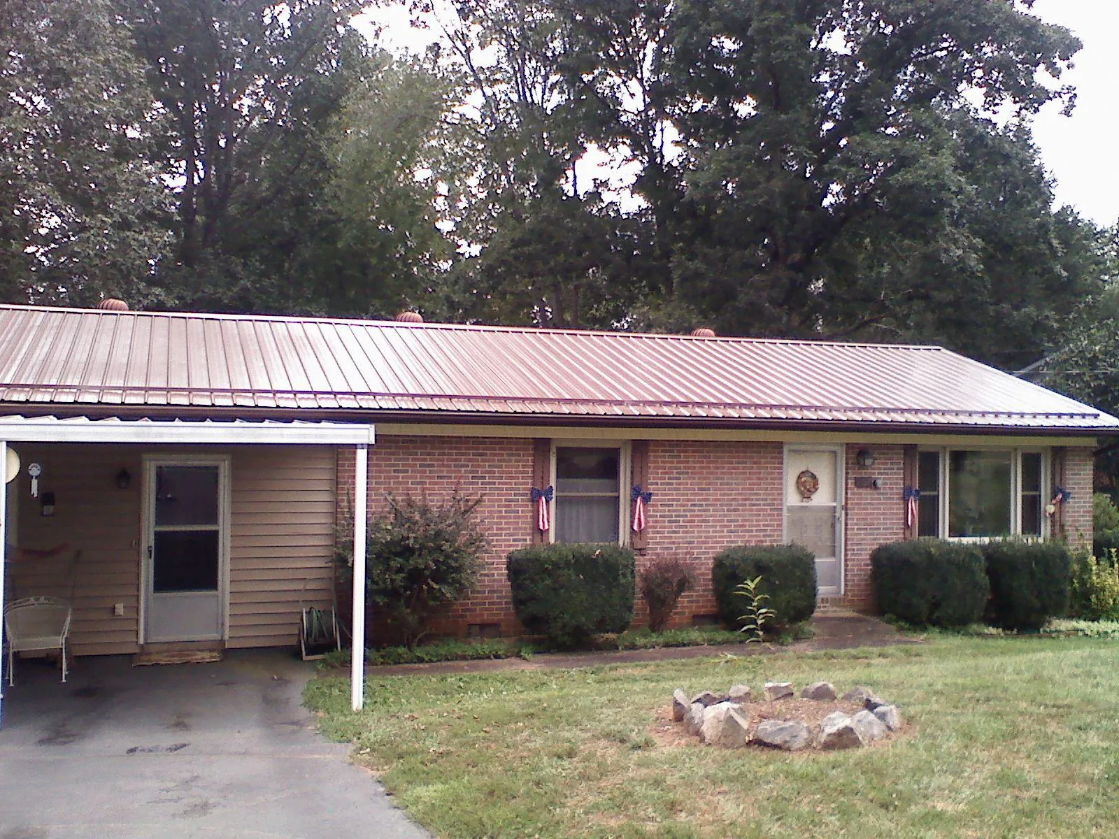 Bronze metal roof and carport on a brick ranch home — Roof Repair work by our crew in Crivitz