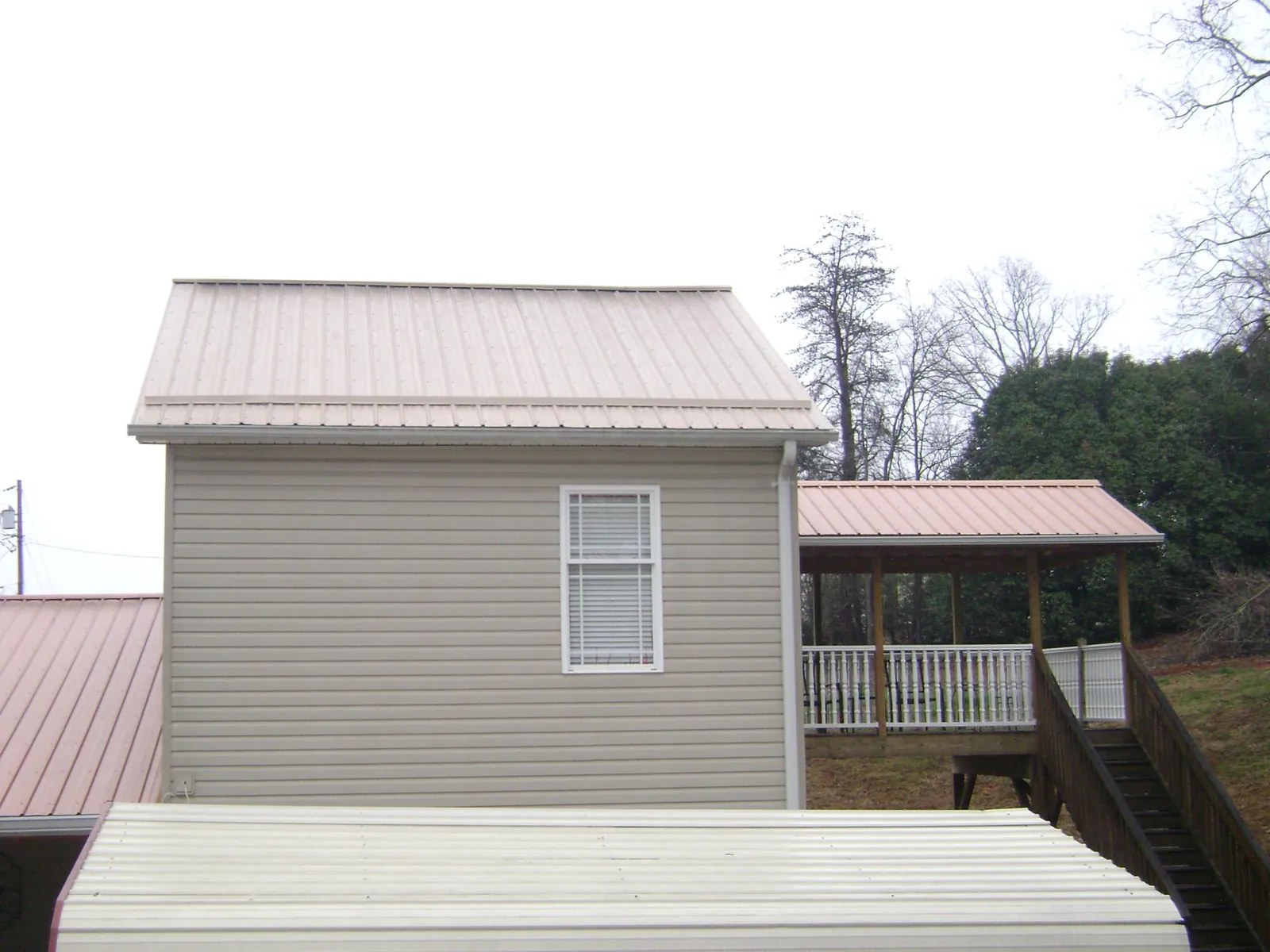 Tan metal roofs on a two story addition and attached porch, from a Roof Replacement job in Crivitz